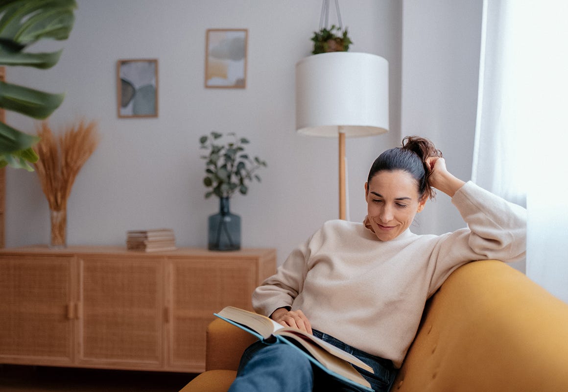Kvinna som sitter i en soffa och läser en bok